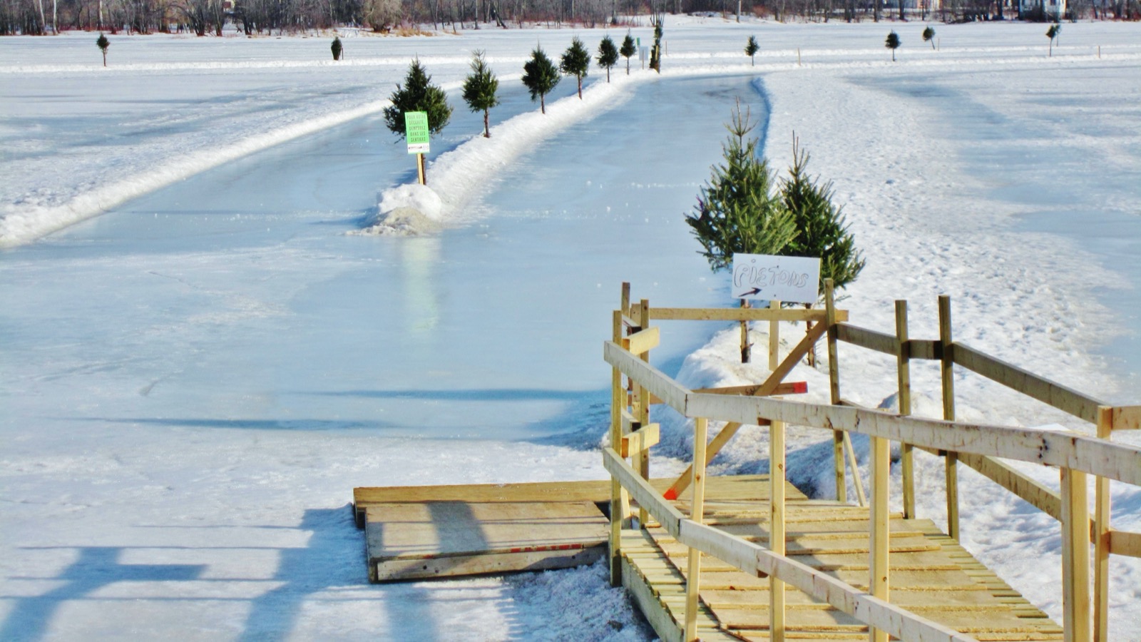 Patinoire dégagée sur la glace de la rivière des Mille Îles, avec une passerelle de bois pour y descendre