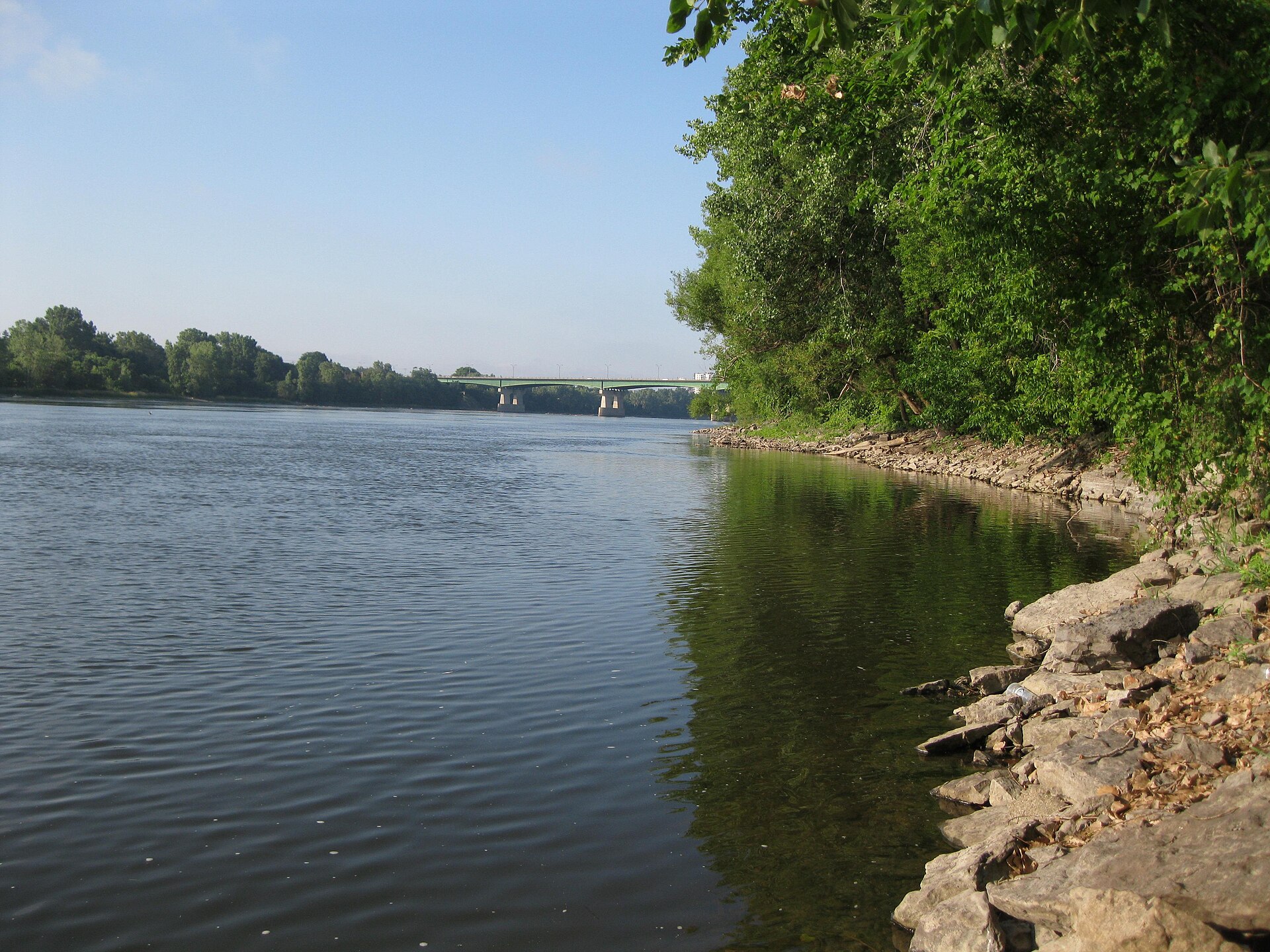 La berge rocheuse de la rivière des Prairies à Saint-Vincent-de-Paul, avec le pont Pie-IX au loin