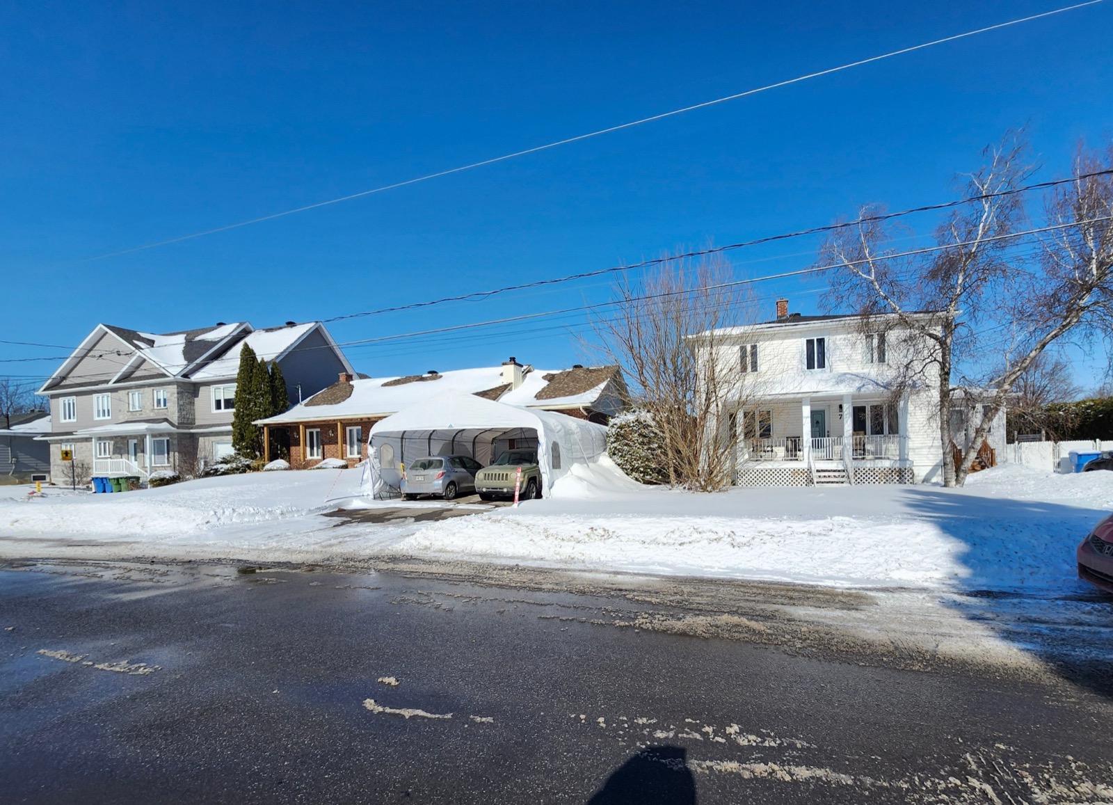 Une rue résidentielle enneigée de Mercier, bordée de maisons familiales