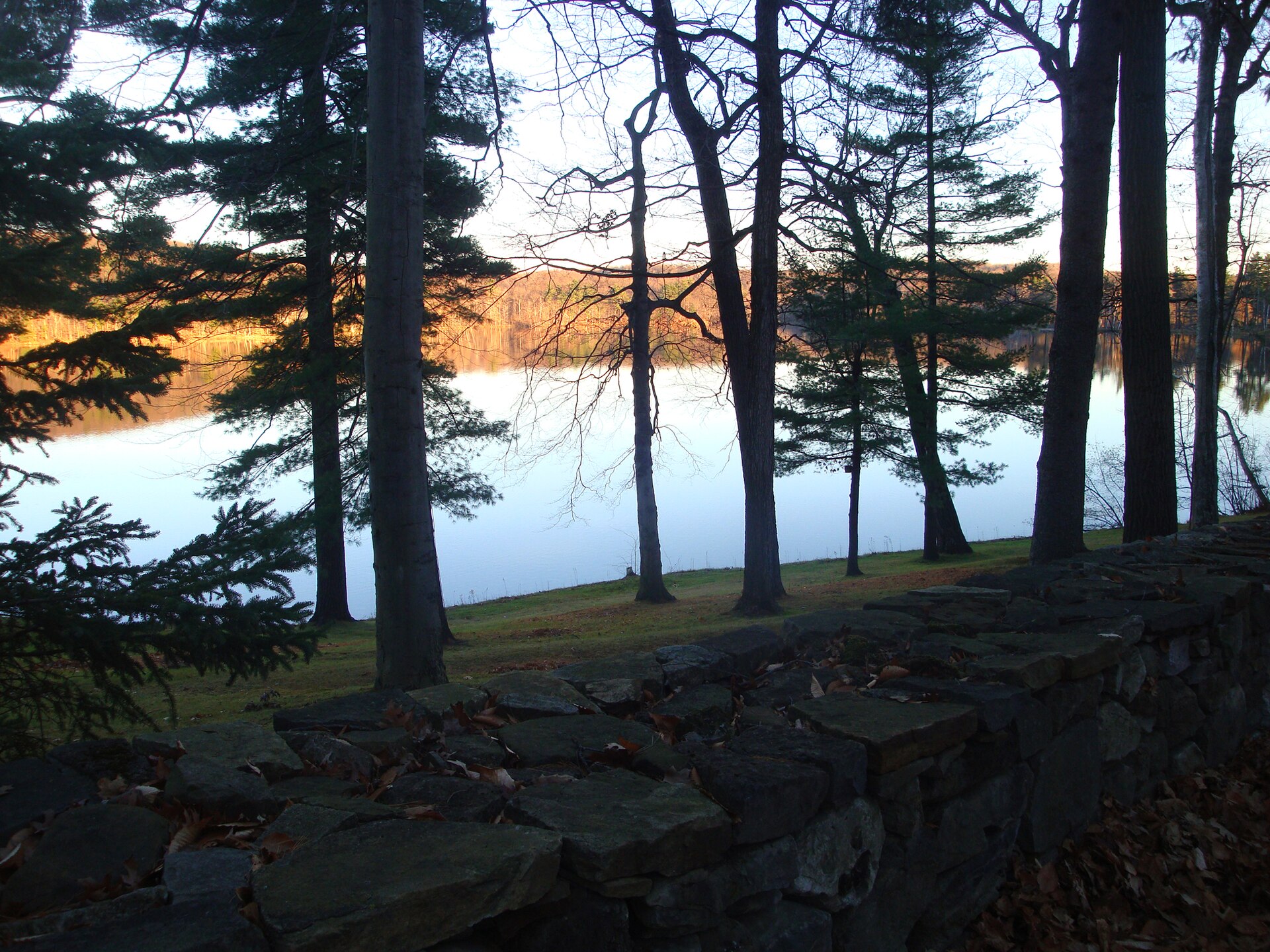 Un lac du parc national du Mont-Saint-Bruno au crépuscule, derrière un muret de pierre