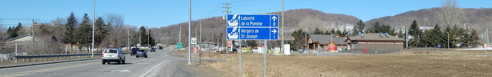 Le chemin d'Oka à Saint-Joseph-du-Lac, avec les panneaux vers les vergers et les collines en arrière-plan