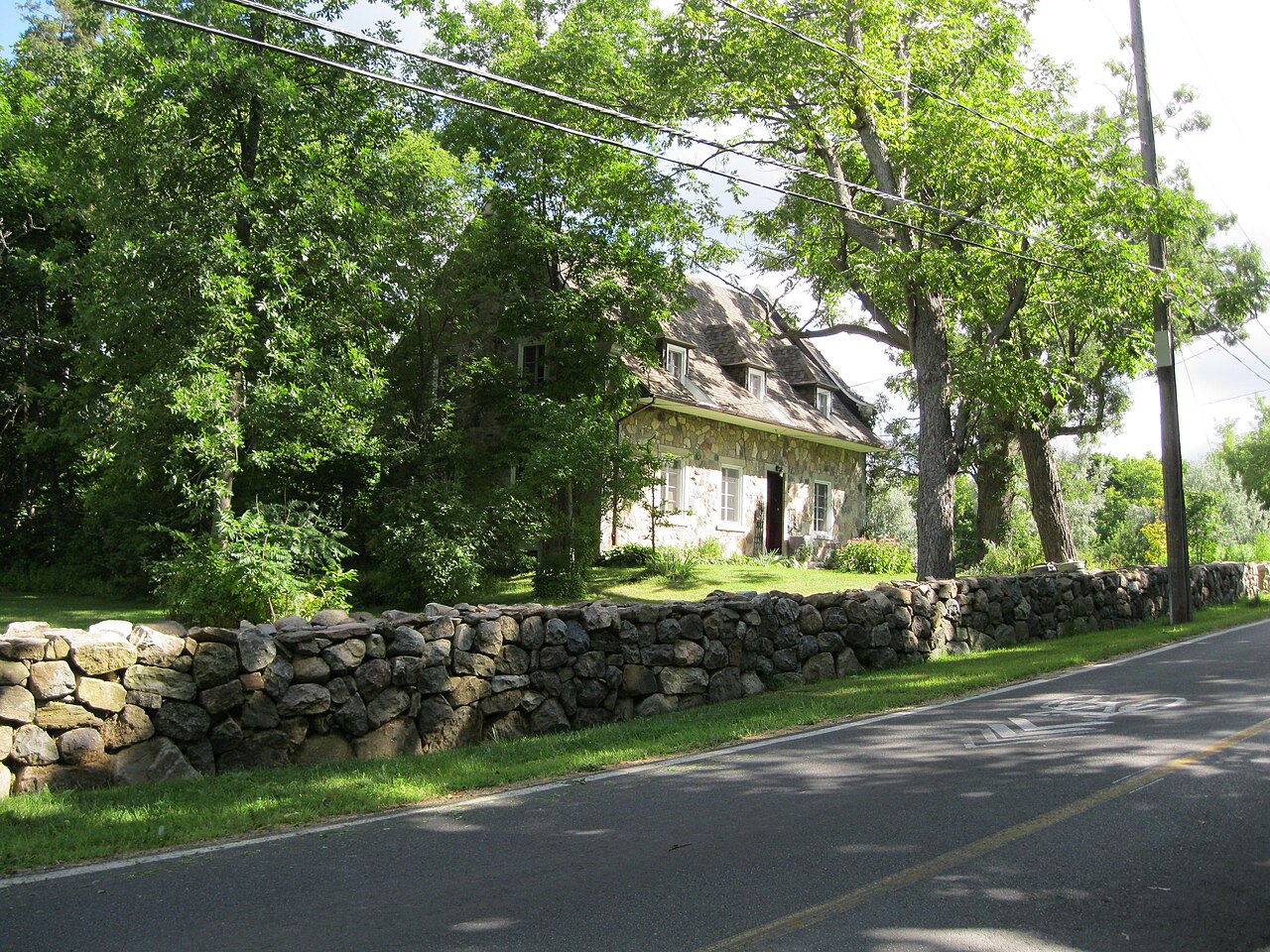Maison ancestrale en pierre derrière son mur de pierres sèches, chemin de Senneville